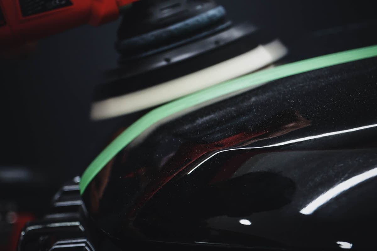 Auto detailer applying ceramic coating to a black sedan in a detail bay